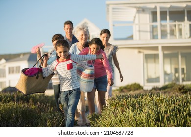 Family walking on beach path outside house
