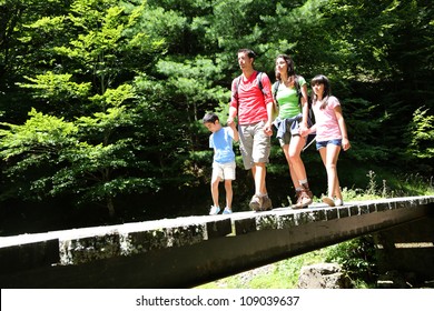 Family walking on a bridge in mountain forest