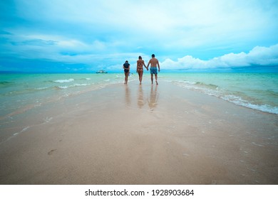                  Family is walking on the white sand beach               