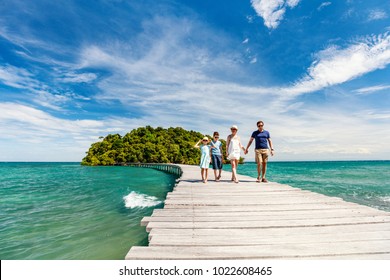 Family walking on wooden pathway leading to beautiful tropical island in Cambodia