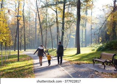 A Family Walking In The Park In Autumn