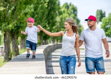 Family Walking In The Park In The Summer. Cheerful Little Boy Playing In The Park With His Parents In The Summer. Dad, Mom And The Kids Played In The Park In The Summer.