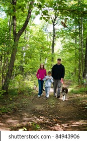 Family Walking Their Dog On A Forest Path