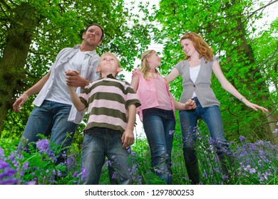 Family Walking Through Forest With Spring Bluebells