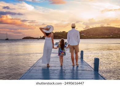 A family walks down a pier in the Caribbean sea during beautiful sunset time at their holiday vacations - Powered by Shutterstock