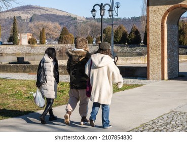 A Family Walks Through The Park. They Are Dressed In Thick Winter Clothes. Rear View. End Of Winter. Family Time - Concept.