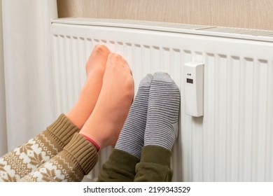 Family In Warm Socks Near The Home Heater In The Cold Season. Heating Season At Home.