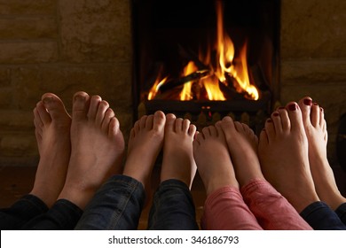 Family Warming Feet By Fire