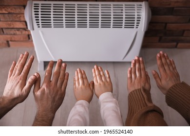 Family Warming Hands Near Electric Heater At Home, Closeup