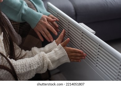 Family Warming Hands Near Electric Heater At Home, Closeup