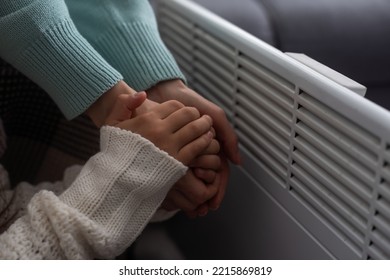 Family Warming Hands Near Electric Heater At Home, Closeup