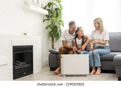 Family Warming Up Near Home Heater At Winter Cold Time. The Symbolic Image Of The Heating Season At Home.