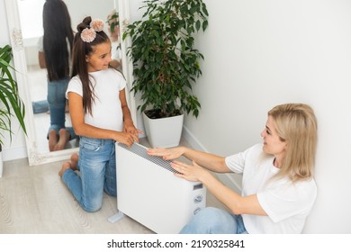 Family Warming Up Near Home Heater At Winter Cold Time. The Symbolic Image Of The Heating Season At Home.