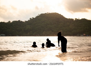 The Family Was Warmly Playing In The Sea As The Sun Set As The Golden Light Shone Through The Mountains And Fell Into The Sea.