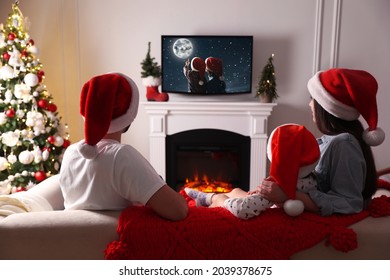 Family Watching Festive Movie On TV In Room Decorated For Christmas, Back View