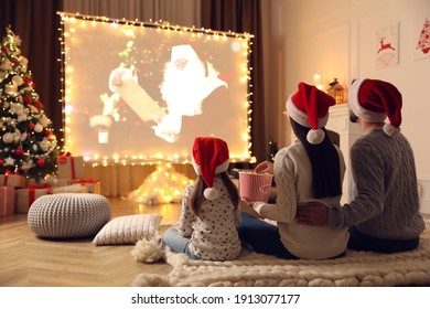 Family Watching Movie On Projection Screen In Room Decorated For Christmas, Back View. Home TV Equipment