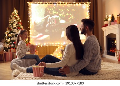 Family Watching Movie On Projection Screen In Room Decorated For Christmas. Home TV Equipment