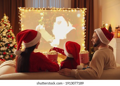 Family Watching Movie On Projection Screen In Room Decorated For Christmas, Back View. Home TV Equipment