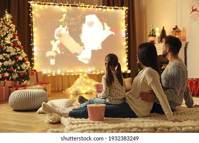 Family Watching Movie On Projection Screen In Room Decorated For Christmas. Home TV Equipment