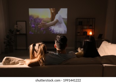 Family Watching Movie On Sofa At Night, Back View