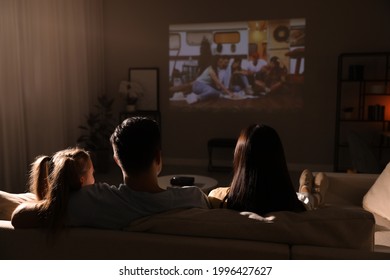 Family Watching Movie On Sofa At Night, Back View