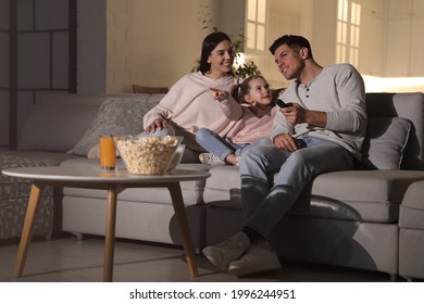 Family watching movie with popcorn on sofa at night - Powered by Shutterstock