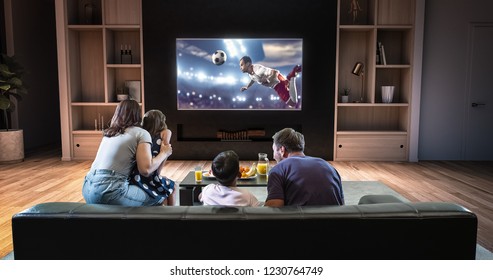 A Family Is Watching A Soccer Moment On The TV And Celebrating A Goal, Sitting On The Couch In The Living Room. The Living Room Is Made In 3D.