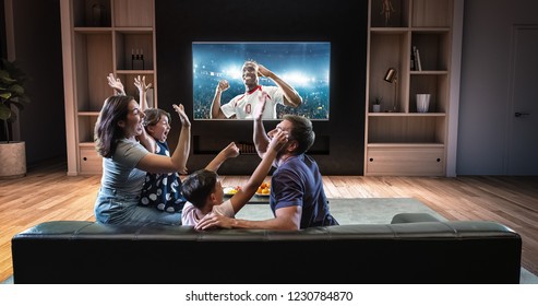 A family is watching a soccer moment on the TV and celebrating a goal, sitting on the couch in the living room. The living room is made in 3D. - Shutterstock ID 1230784870