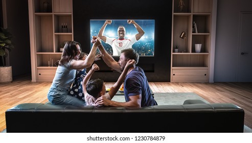 A family is watching a soccer moment on the TV and celebrating a goal, sitting on the couch in the living room. The living room is made in 3D. - Shutterstock ID 1230784879