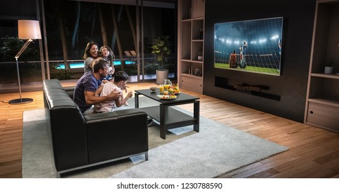A family is watching a soccer moment on the TV and celebrating a goal, sitting on the couch in the living room. The living room is made in 3D.