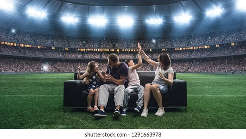 A family is watching a soccer moment, sitting on the couch located in the middle of the soccer stadium. Stadium and crowd are made in 3D. - Powered by Shutterstock