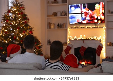 Family watching TV in cosy room, back view. Christmas atmosphere - Powered by Shutterstock