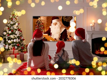 Family watching TV movie in room decorated for Christmas, back view
