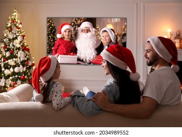 Family Watching TV Movie In Room Decorated For Christmas