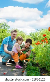 Family Watering Flowers In Their Garden