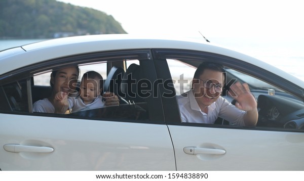 The family waved goodbye inside the white car on\
the beach.
