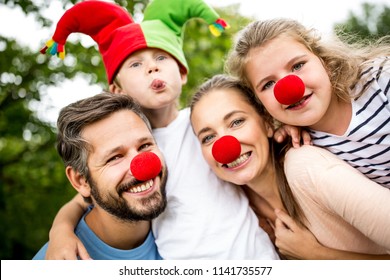 Family Wearing Costumes And Red Nose Having Fun At Carnival 