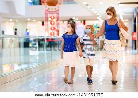 Family wearing face mask in shopping mall in Asia. Mother and children wear facemask during coronavirus and flu outbreak in China. Virus and illness protection. Kids in masks in public crowded place.