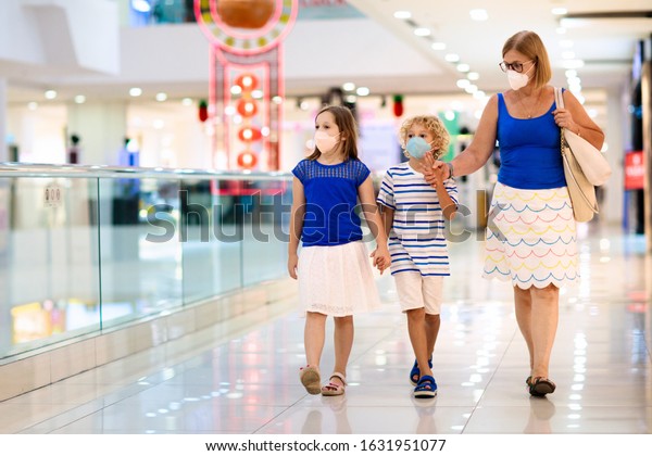Family wearing face mask in shopping mall in Asia.\
Mother and children wear facemask during coronavirus and flu\
outbreak in China. Virus and illness protection. Kids in masks in\
public crowded place.