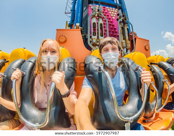 Family wearing a medical mask during COVID-19
coronavirus at an amusement
park