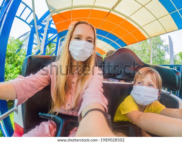 Family wearing a medical mask during COVID-19
coronavirus at an amusement
park
