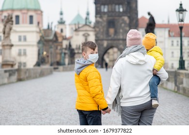 Family Wearing A Medical Masks On Charles Bridge In Prague. Coronavirus Epidemic Concept