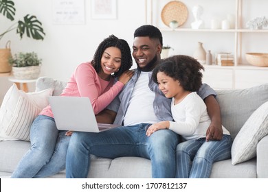 Family Weekend. Cheerful Black Parents And Their Little Daughter Using Laptop At Home Together, Watching Movie Or Browsing Internet, Free Space