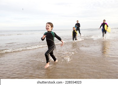 Family in Wetsuits on the Beach Playing in the Sea - Powered by Shutterstock