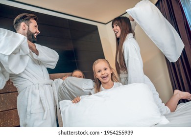 Family In White Robes Having A Pillow Fight