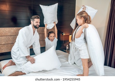 Family In White Robes Having A Pillow Fight