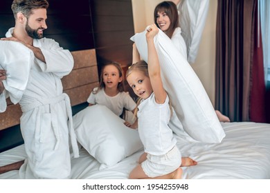 Family In White Robes Having A Pillow Fight