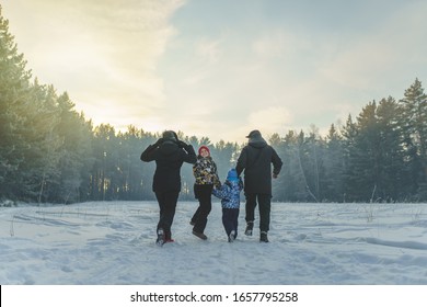 Family In The Winter Forest Park At Sunset