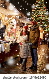 Family, Winter Holidays And Celebration Concept - Happy Mother, Father And Little Daughter At Christmas Market On Town Hall Square In Tallinn, Estonia Over Snow