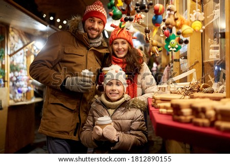 family, winter holidays and celebration concept - happy mother, father and little daughter with takeaway drinks at christmas market on town hall square in tallinn, estonia
